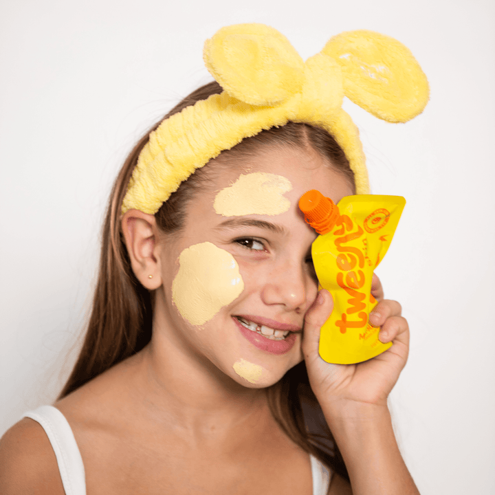 Tween applying Multi-Masker turmeric clay face mask while holding product, fun skincare routine for tweens and teens